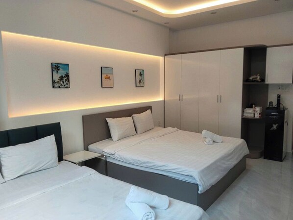 Une chambre d’hôtel moderne avec un grand lit, des tables de chevet, une armoire et des œuvres d’art accrochées au mur.