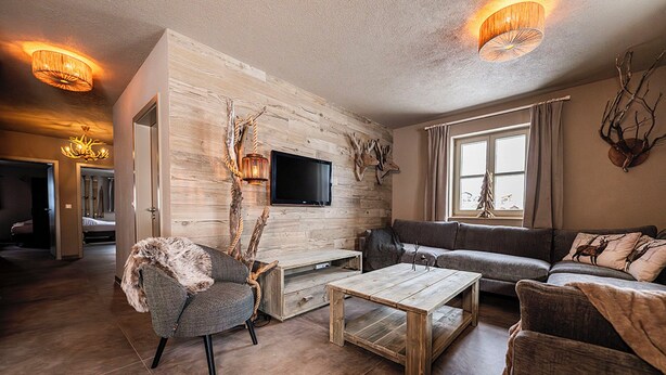 A modern living room with a wooden wall, a flat-screen TV, a sofa, and a coffee table. - 3-bedroom apartment Frauenschuh 2-10 pers (110m2), terrace & view of the slopes (Berwang)