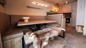A modern kitchen with a wooden bench, a hanging light fixture, and a fur-covered stool. - 3-bedroom apartment Frauenschuh 2-10 pers (110m2), terrace & view of the slopes (Berwang)