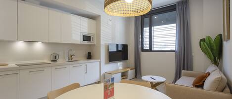Una cucina moderna con mobili bianchi, un forno a microonde e un lampadario intrecciato.