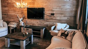 Een moderne woonkamer met een houten wand, een flatscreen televisie, een houten salontafel en een bank.