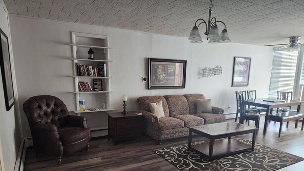 A living room with a brown leather armchair, a patterned sofa, a coffee table, and a bookshelf.
