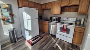 A modern kitchen with wooden cabinets, a stainless steel refrigerator, a microwave, a dishwasher, and an oven.