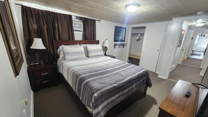 A bedroom with a bed, bedside tables, a lamp, a wardrobe, and a mirror.