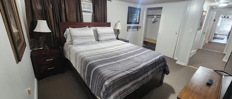 Une chambre à coucher comprenant un lit, des tables de chevet, une lampe, une armoire et un miroir.