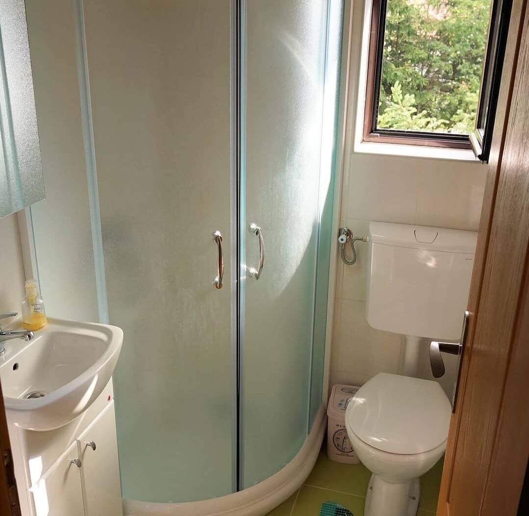 A bathroom with a glass shower enclosure, a toilet, and a sink.