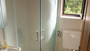 Ein Badezimmer mit Duschkabine, Toilette und Waschbecken.