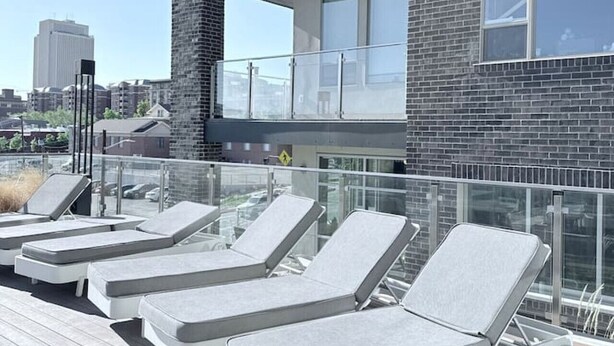 A rooftop deck with lounge chairs and a glass balustrade.