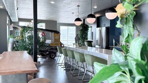 A modern kitchen with a bar area, green chairs, and a large window.