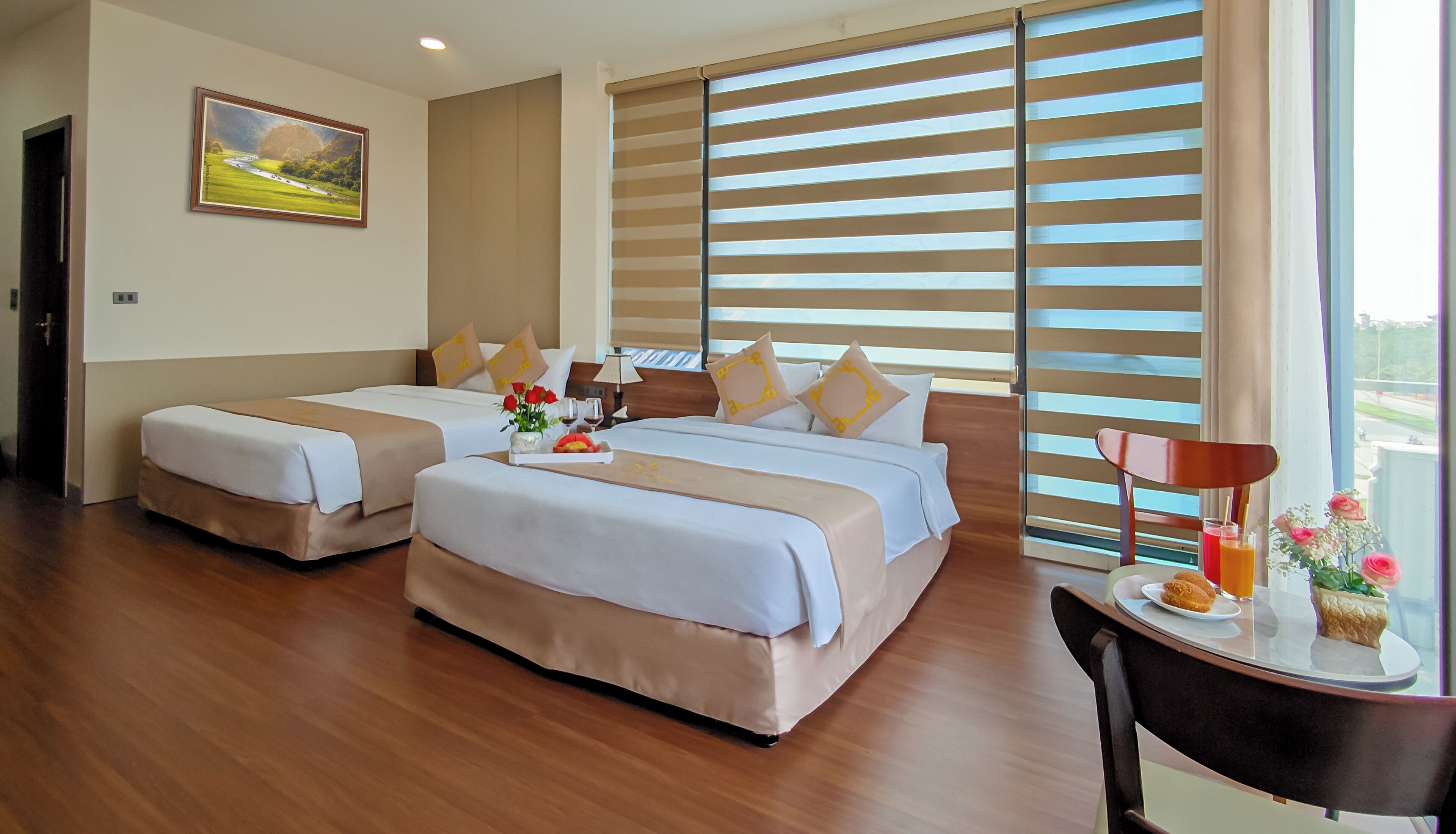 Habitación de hotel con dos camas, un cuadro en la pared y un ventanal con persianas.