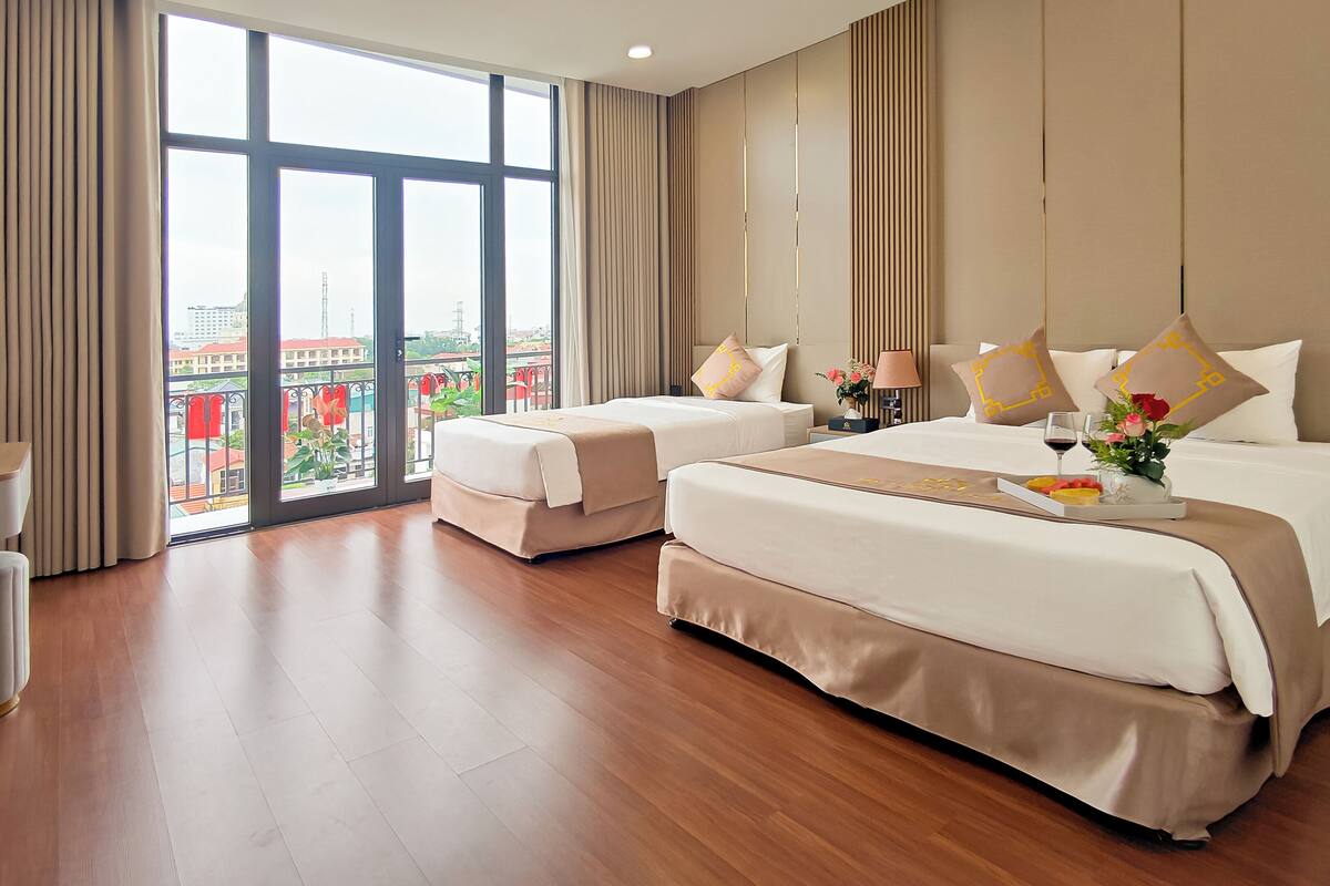 A hotel room with two beds, a desk, and a view of the city.
