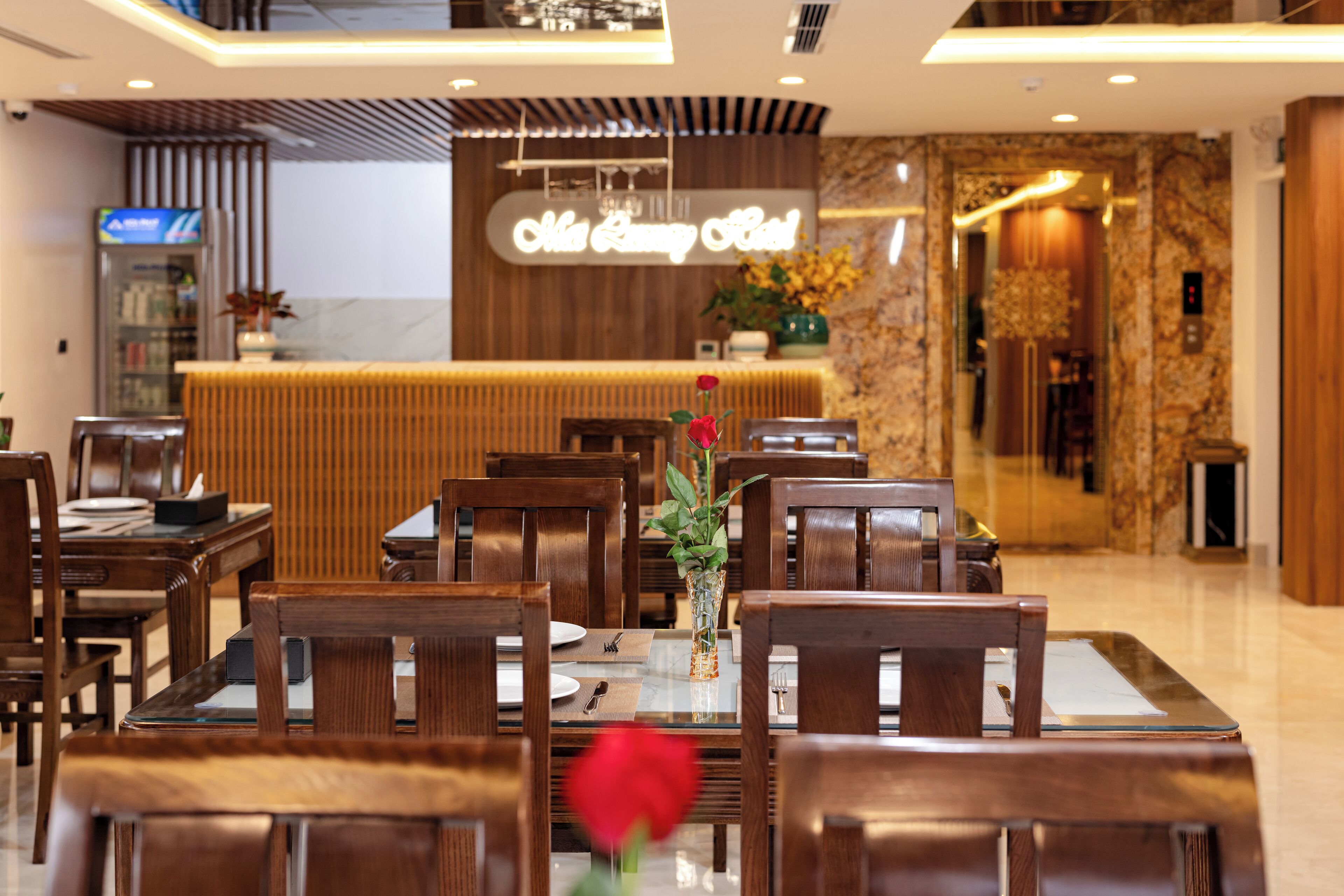 A hotel lobby with wooden furniture, a reception desk, and a neon sign.