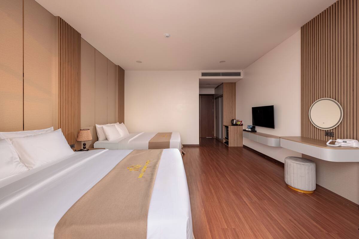 A hotel room with two beds, a TV, a mirror, and a small table.