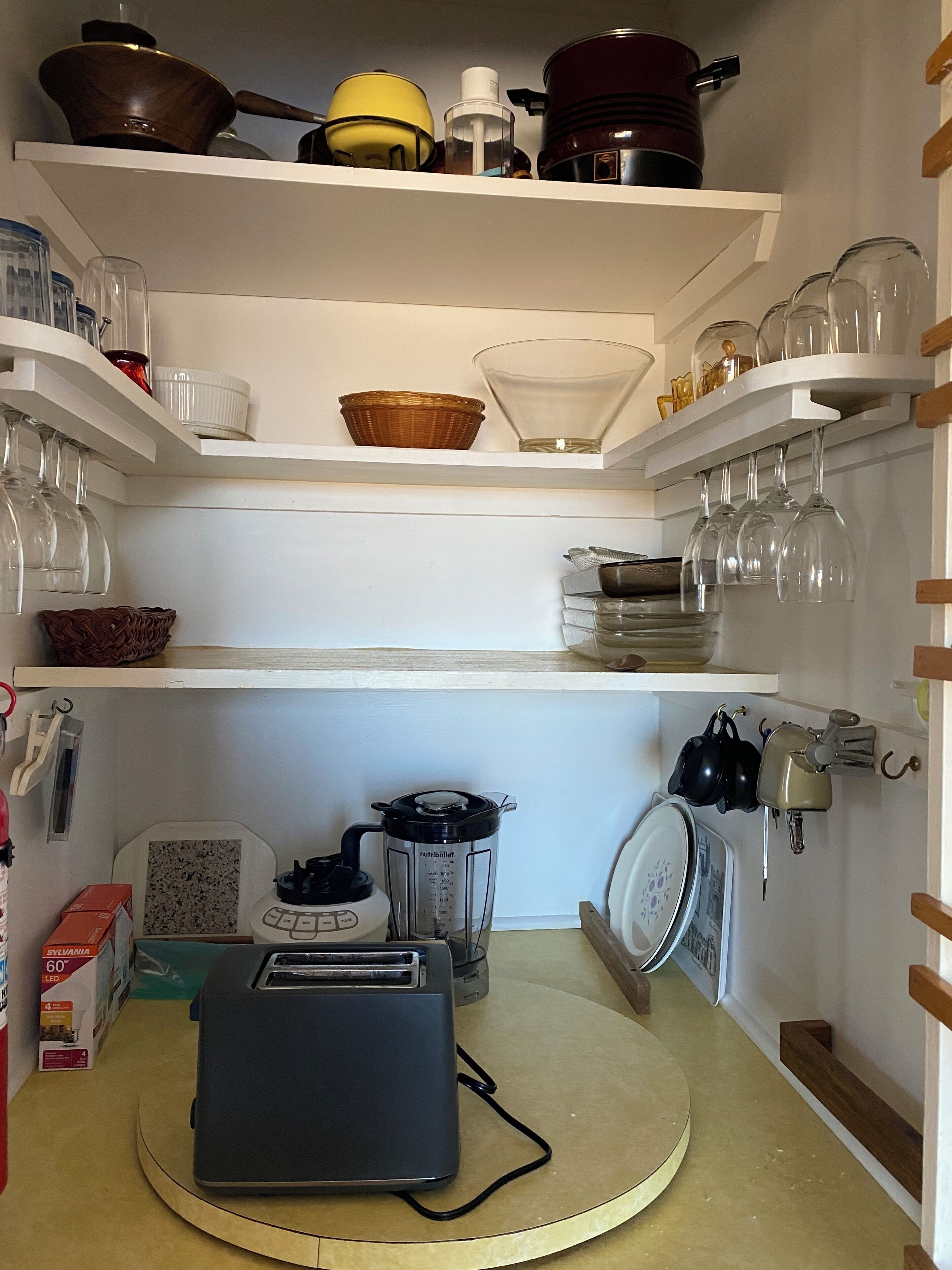 Una cocina con estantes blancos que sostienen diferentes utensilios de cocina, un tostador y una licuadora sobre la encimera.