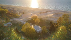An aerial view of a coastal property with a house surrounded by trees, a dock, and a beach. - Agate Beach House - waterfront in Grand Marais (Grand Marais)