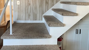 A staircase with a wooden wall background, white steps, and a handrail. - Agate Beach House - waterfront in Grand Marais (Grand Marais)