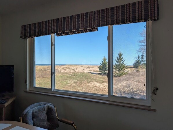 A room with a large window overlooking a grassy field and trees.