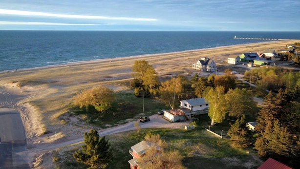 A coastal area with a beach, houses, and a lighthouse in the distance. - Agate Beach House - waterfront in Grand Marais (Grand Marais)