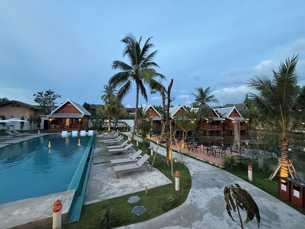 A resort with a swimming pool, lounge chairs, and wooden cabins. - The Jam Boutique Hotel (Luang Prabang)