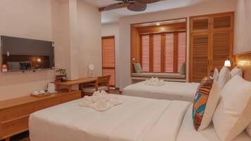 A hotel room with two beds, a desk, a chair, a television, and a ceiling fan.