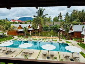 A resort with a swimming pool, lounge chairs, and palm trees. - The Jam Boutique Hotel (Luang Prabang)