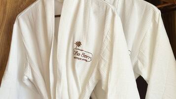 Deux robes blanches sont suspendues à un portant en bois, dans une pièce également en bois.