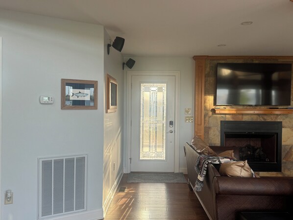 A living room with a fireplace, a television mounted above it, and a door with a glass panel.