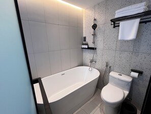 Un baño moderno con una bañera independiente, inodoro y cabezal de ducha.