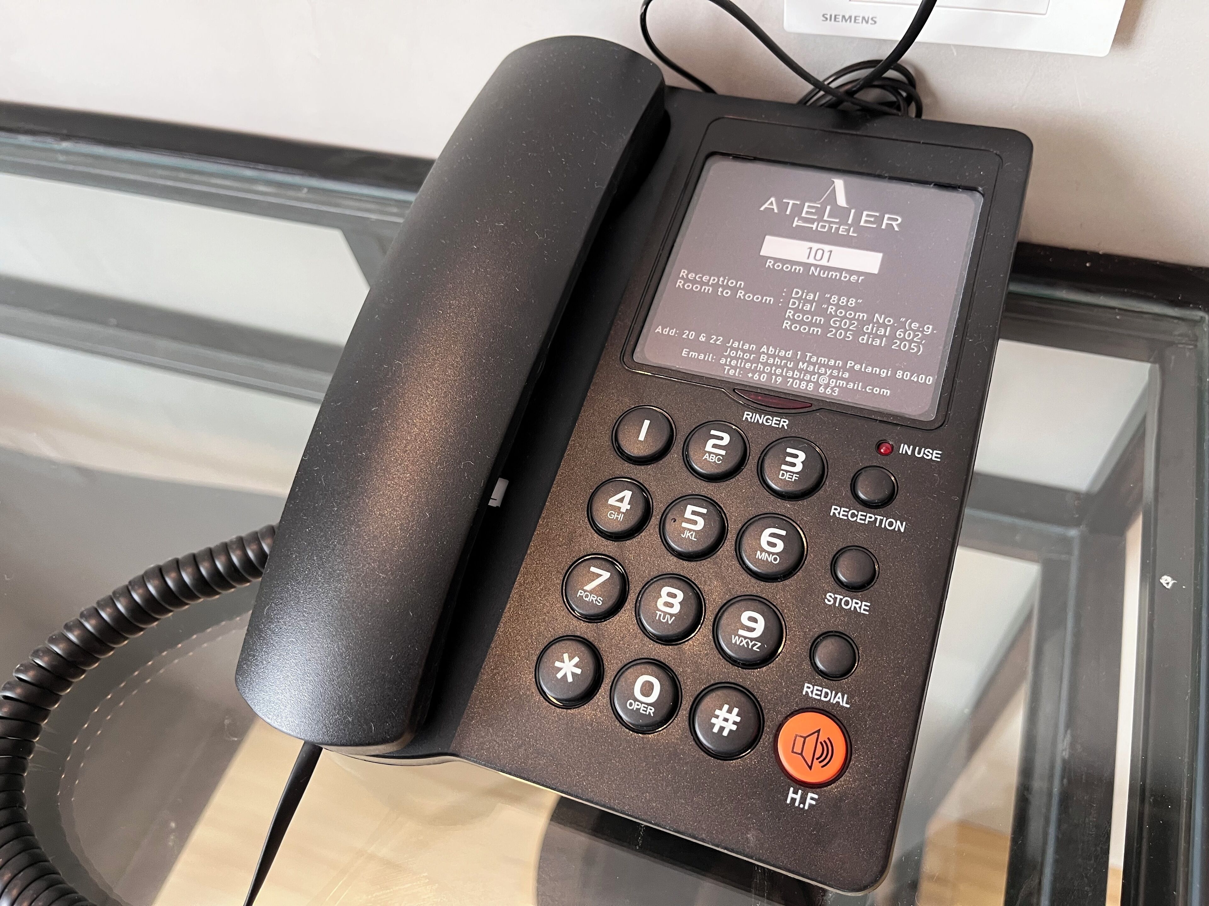 Teléfono de recepción de hotel con teclado y pantalla mostrando información de habitaciones.