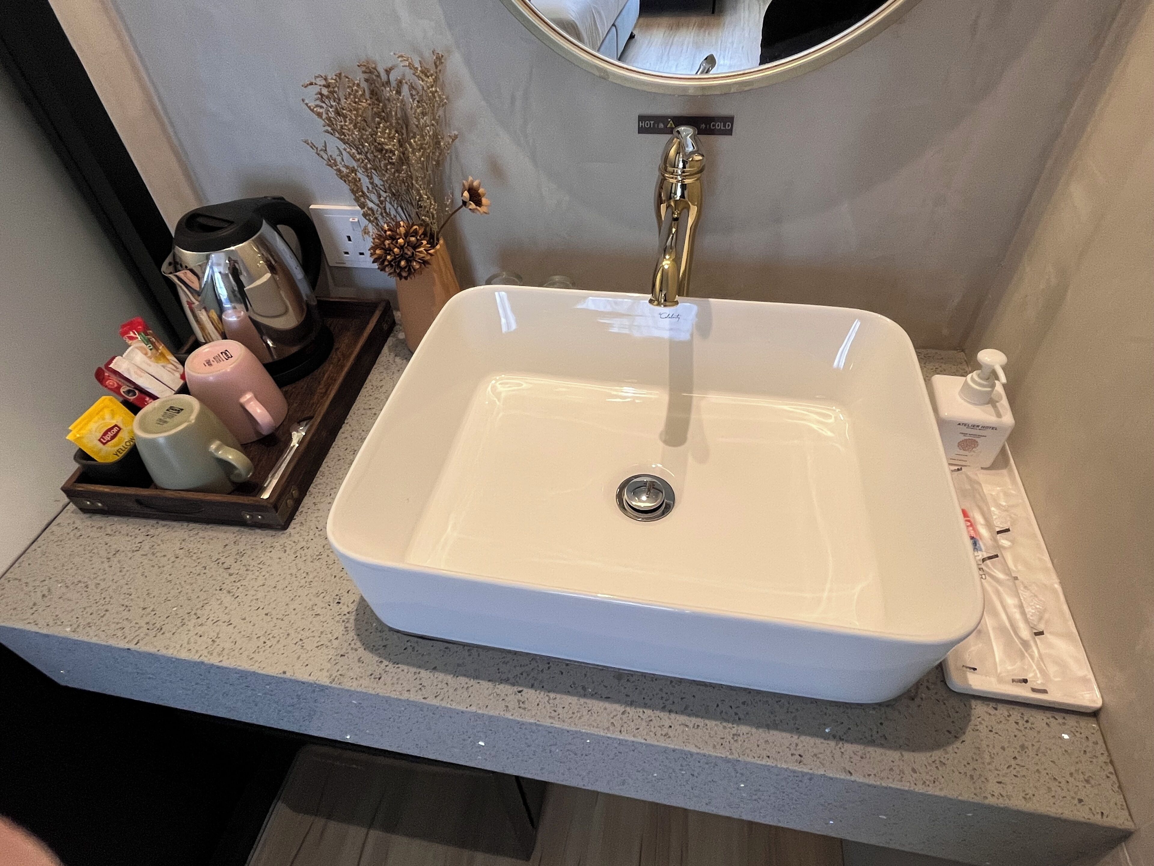 Ein Badezimmer mit einem weißen Waschbecken, einem Spiegel darüber und Pflegeprodukten auf der Ablagefläche.
