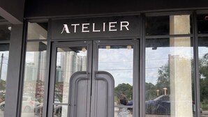 Un escaparate con un amplio ventanal y un letrero que dice "ATELIER".