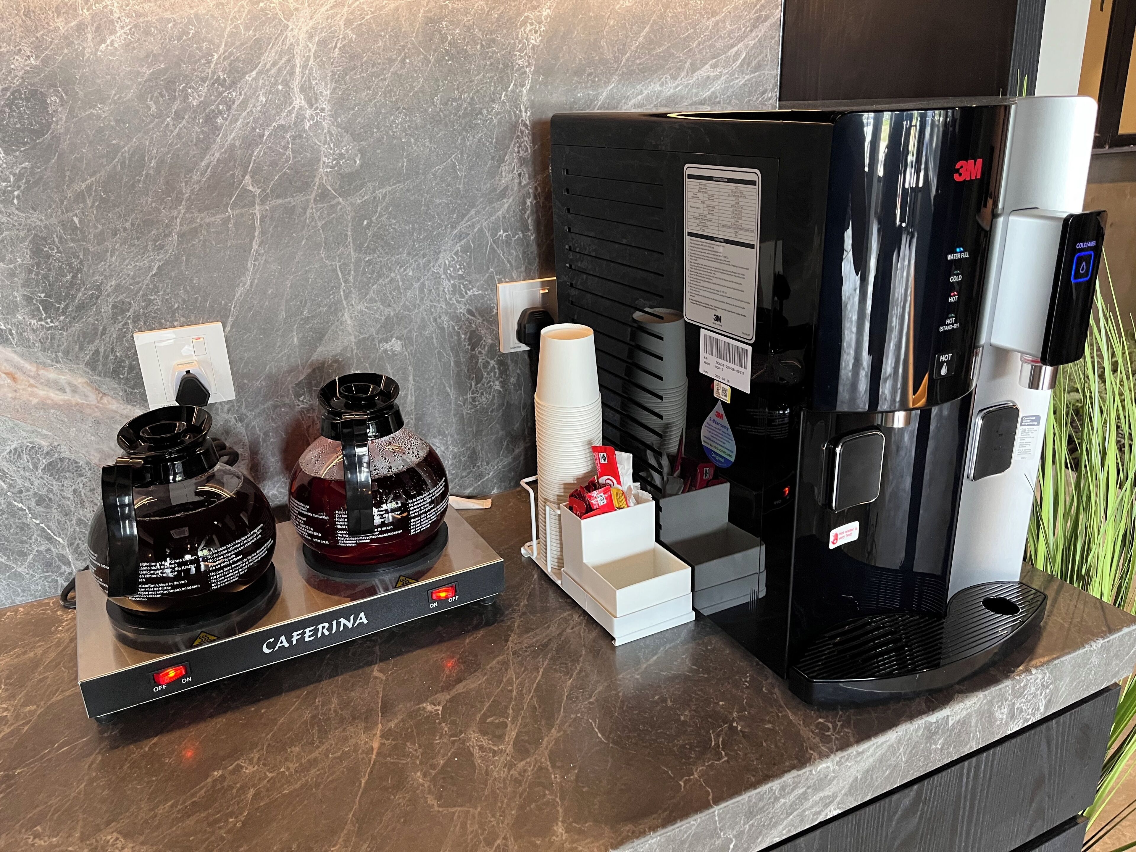 Uma máquina de café e dois dosadores sobre uma bancada de mármore.