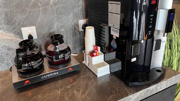 Uma máquina de café e dois dosadores sobre uma bancada de mármore.