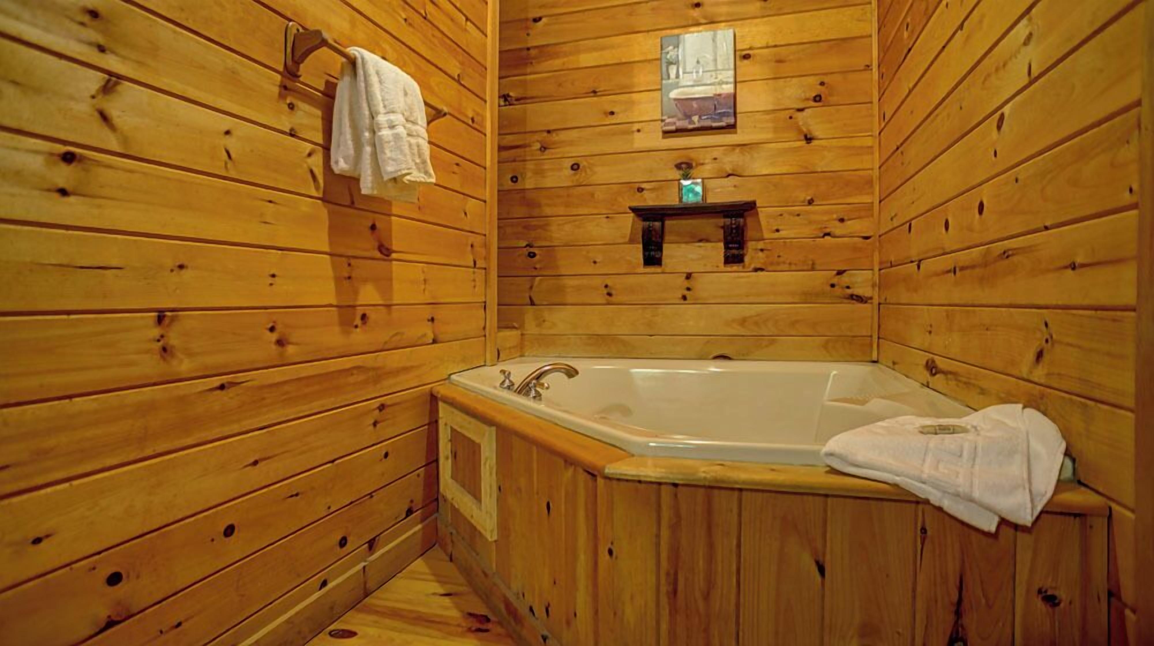 Ein Badezimmer einer Holzhütte mit einer Badewanne, einem Waschbecken und einem Handtuchhalter.