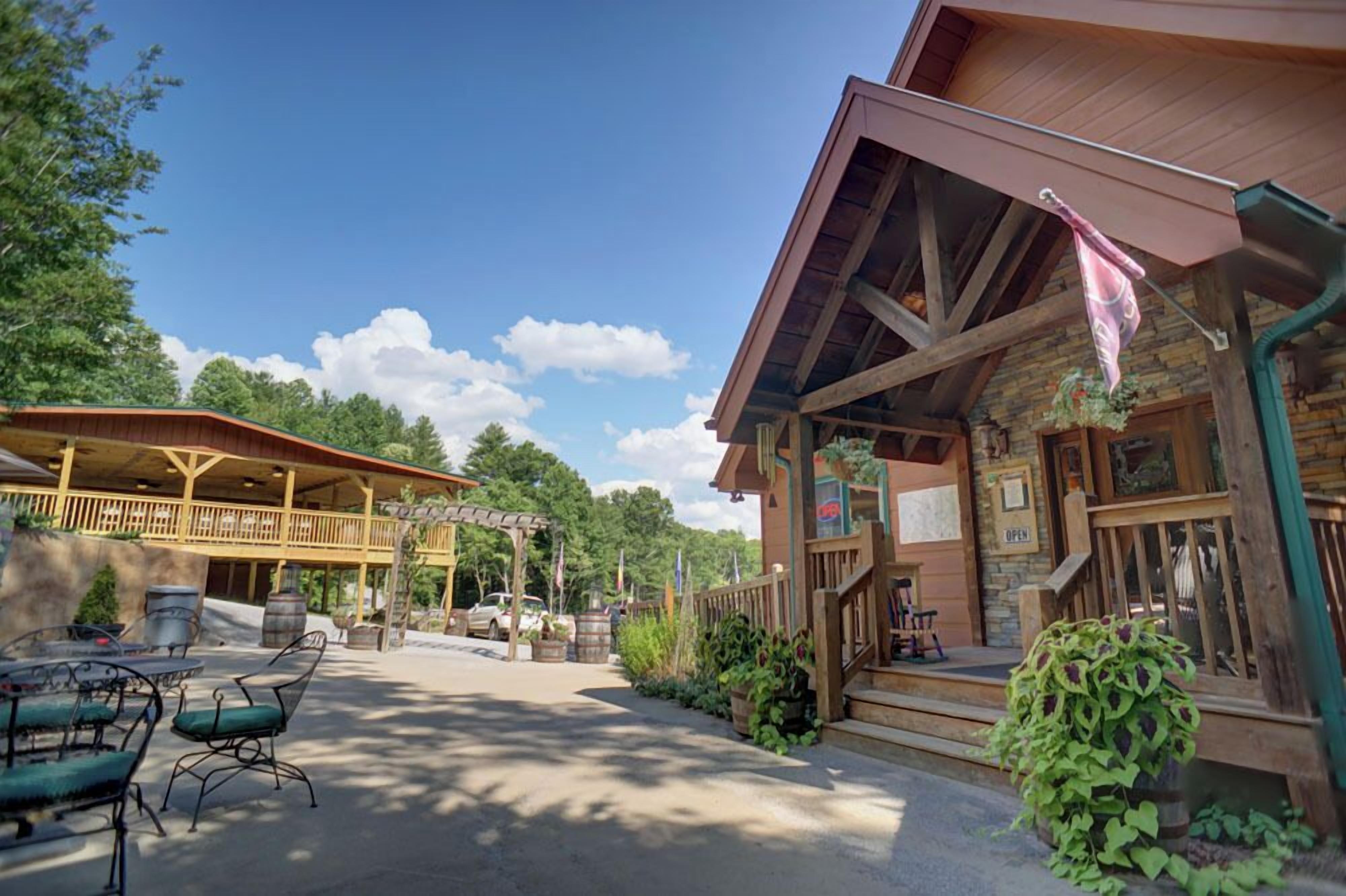 A rustic lodge with a covered patio, outdoor seating, and a stone facade.