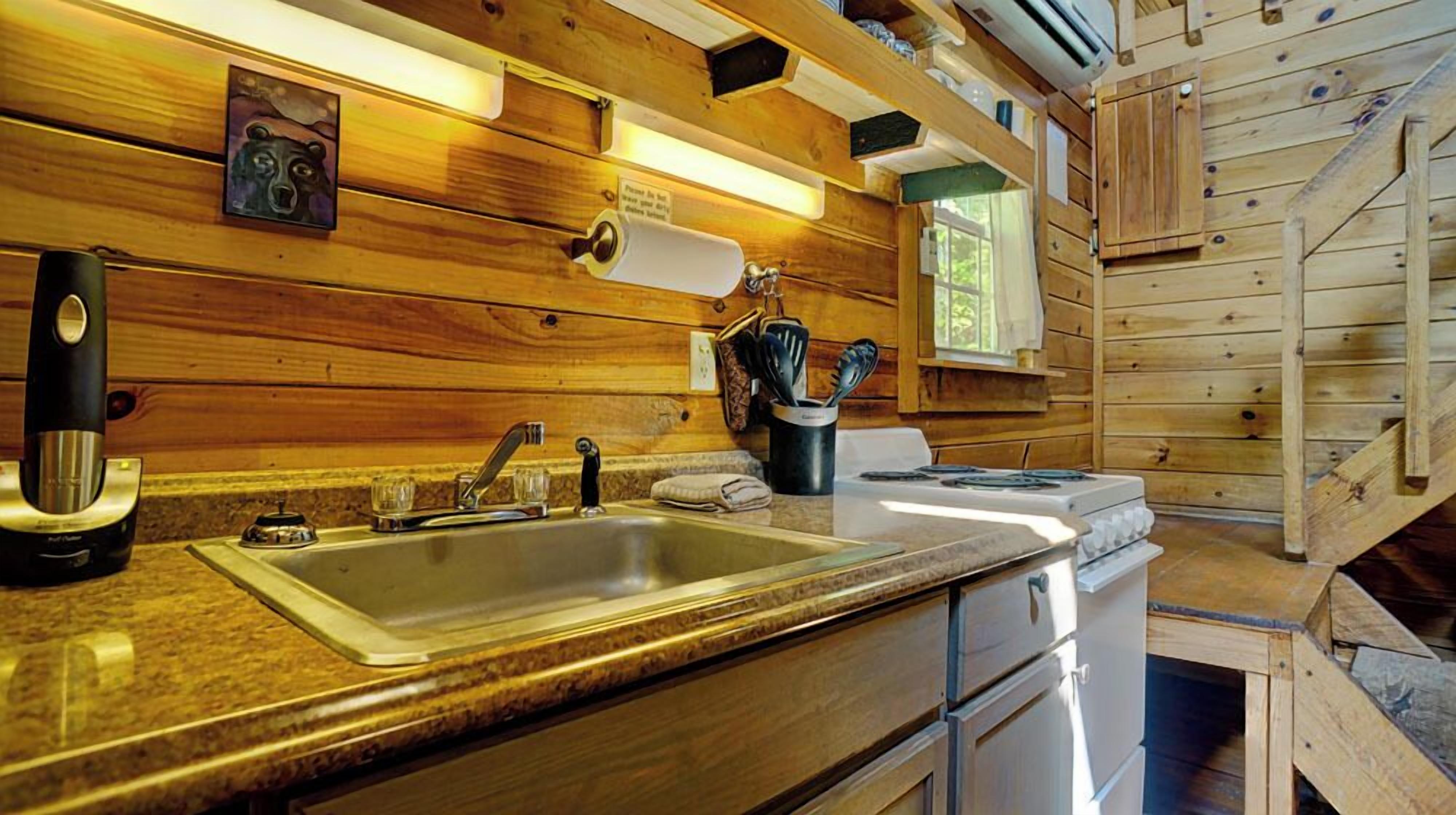 Une cuisine rustique aménagée dans une cabane en bois, avec un plan de travail en granit, un évier en acier inoxydable et une cuisinière.