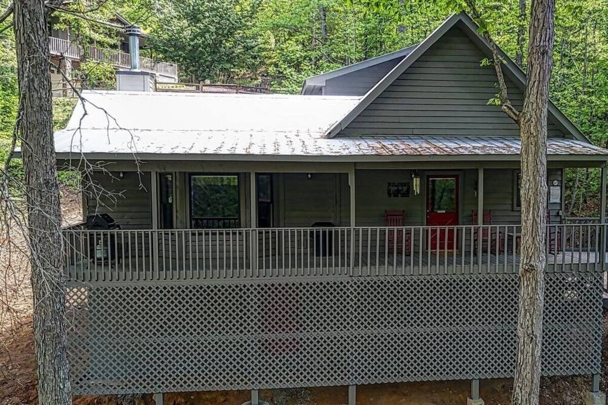 A cabin with a covered porch and a fenced deck area.