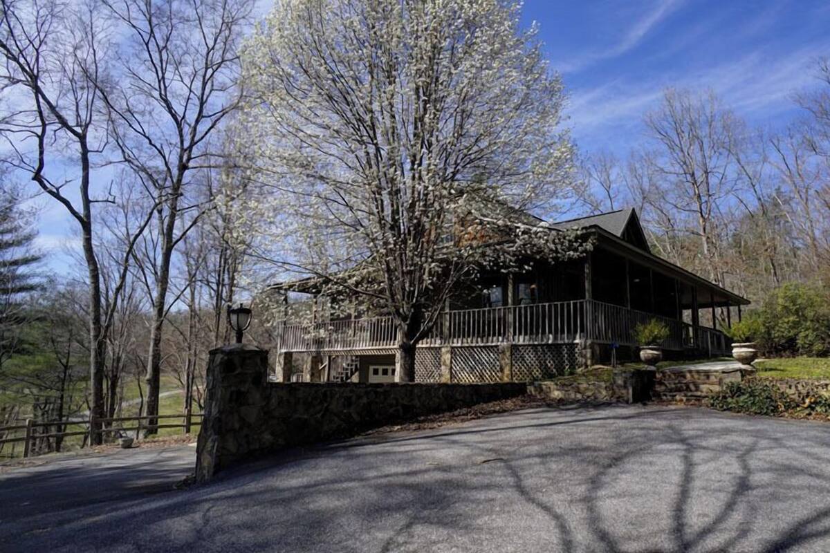 A rustic cabin with a stone foundation, a wooden deck, and a porch.
