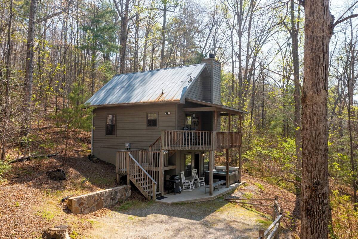 A cabin with a metal roof, a porch, and a deck.