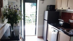 A kitchen with a refrigerator, microwave, and stove. There is a door leading to a balcony with plants. - Welcome to the "Lydmalida" gîte, the Ardèche is waiting to welcome you! (Les Ollières-sur-Eyrieux)