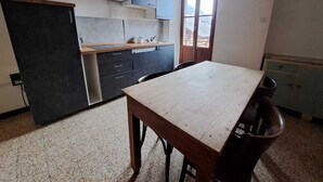 A compact kitchen with dark cabinets, a wooden table, and a window.