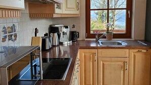 Una cocina con un ventanal grande, una estufa, un lavamanos y armarios de madera.