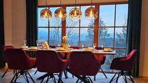 Un comedor con una mesa de madera, sillas rojas y un frutero en el suelo.