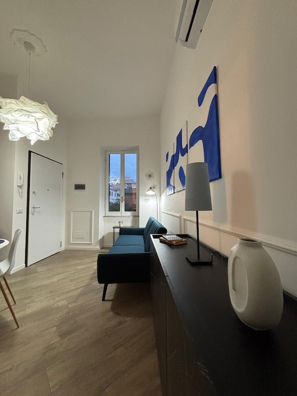 A modern living room with a sofa, a dining table, and a large window.