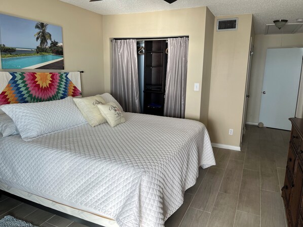Un dormitorio con cama, armario, puerta y un cuadro en la pared.