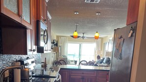 A modern kitchen with wooden cabinets, a large island, stainless steel appliances, and a ceiling fan.
