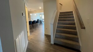 A hallway with a staircase leading to a dining area.