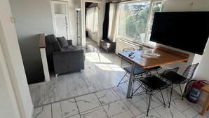 Ein modernes Zimmer mit Essbereich, einer Couch, einem Fernseher und einem Feuerlöscher.