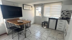 Eine kleine Küche mit Essbereich, einer Waschmaschine und einem großen Fernseher.