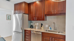 A modern kitchen with wooden cabinets, stainless steel appliances, a granite countertop, and a built-in dishwasher.